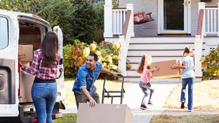 A family carries moving boxes into their new home.