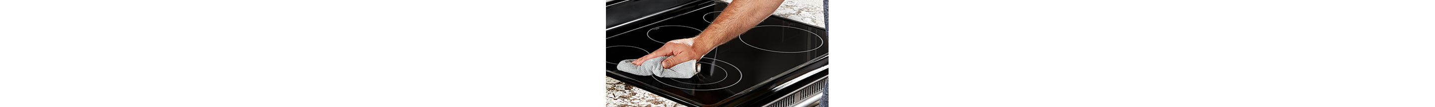Une main essuie une table de cuisson à induction avec un chiffon bleu