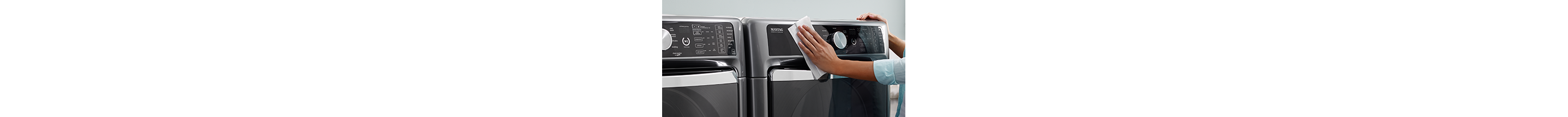 A person wipes down a washing machine control panel.
