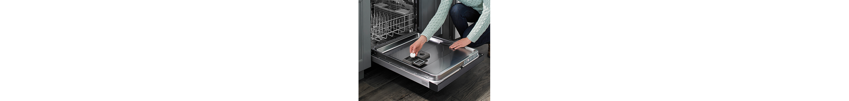 A person places a dishwasher cleaning tablet in the detergent dispenser.