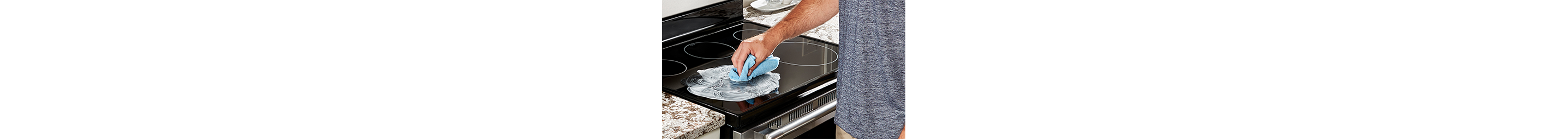 A person applies cooktop cleaner to a glass cooktop.